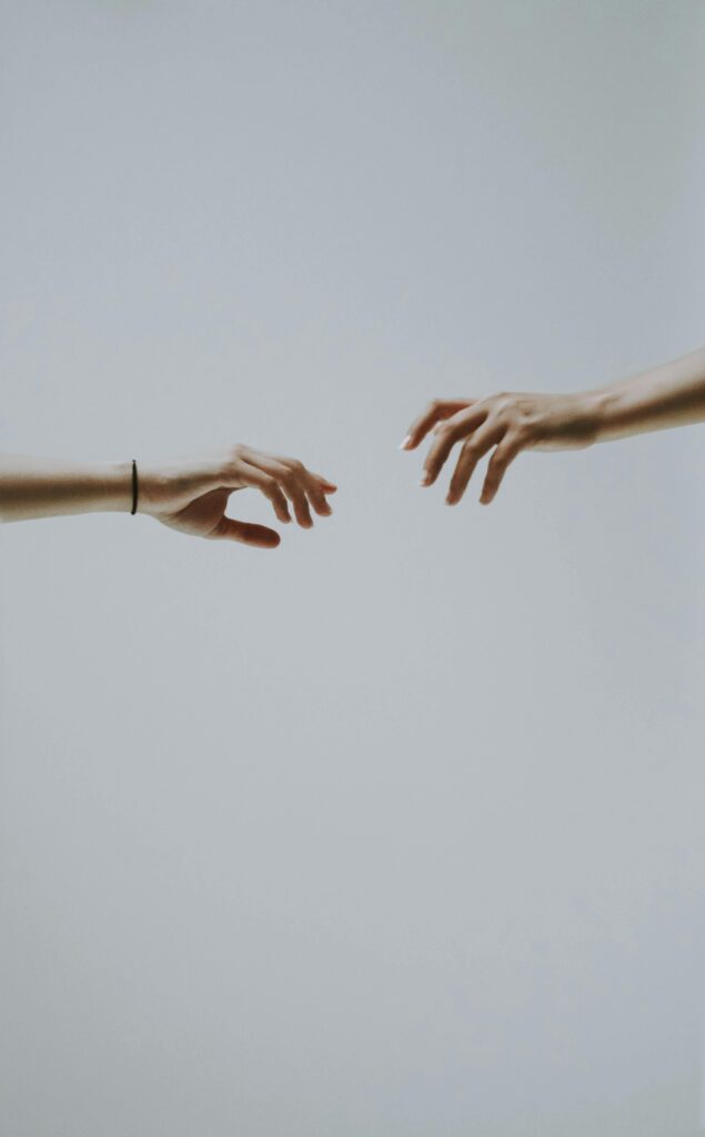 Two hands reaching towards each other against a minimalistic background, symbolizing connection and support.